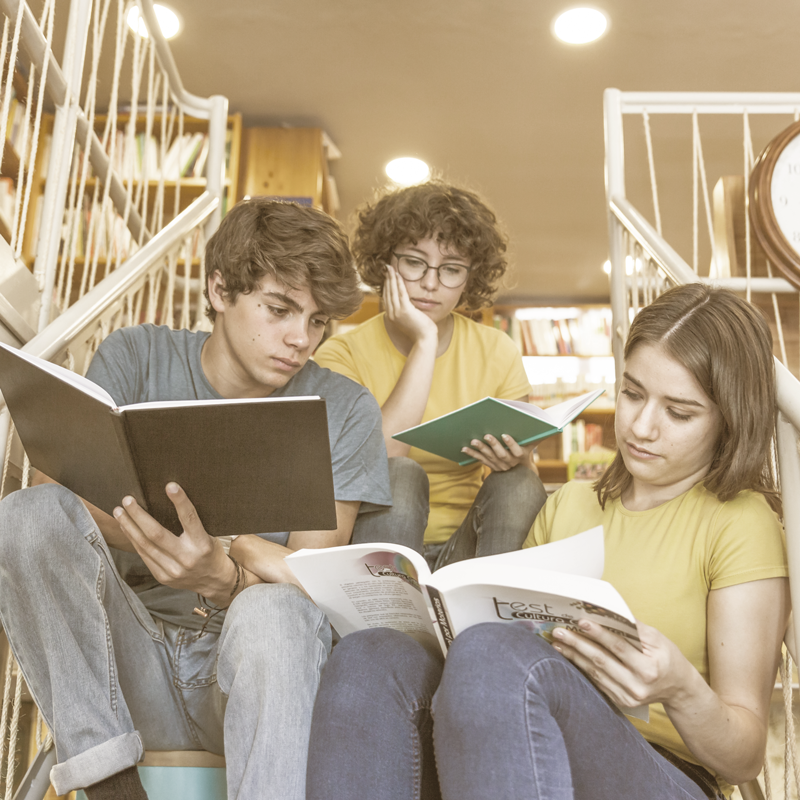 Jovens lendo livro na escada do colégio